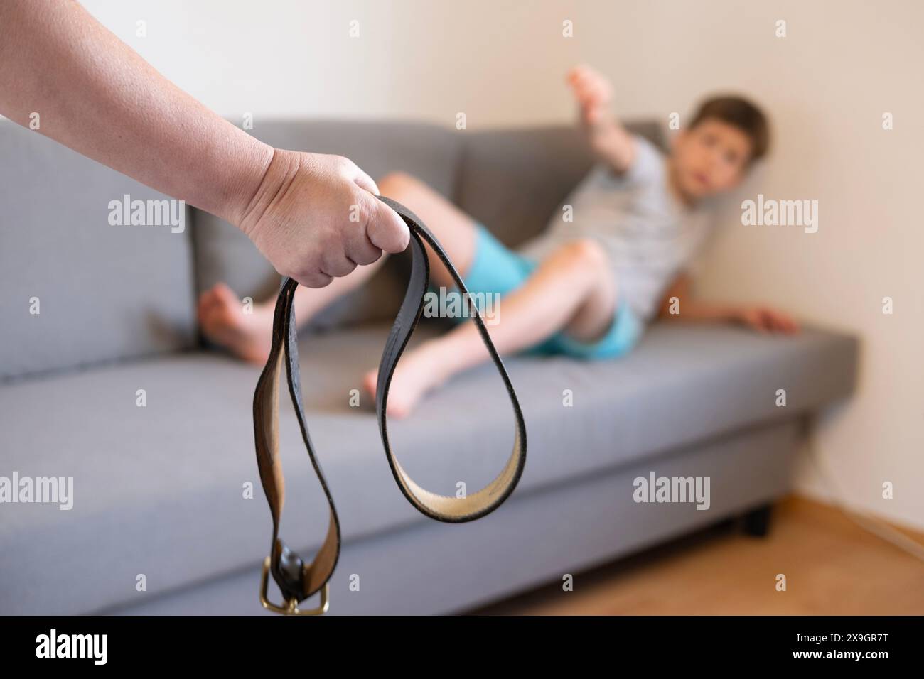 woman with leather belt in hand confronts child, naughty son, authoritarian parental discipline and punishment, Family conflict and generation gap, Pa Stock Photo