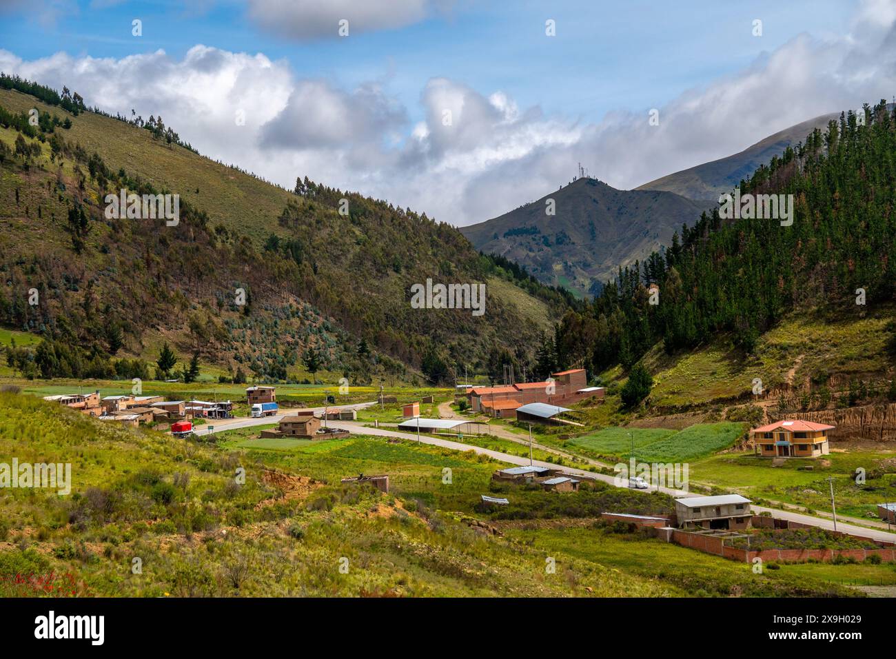 View of a village nestled in a valley of pine trees surrounded by green ...