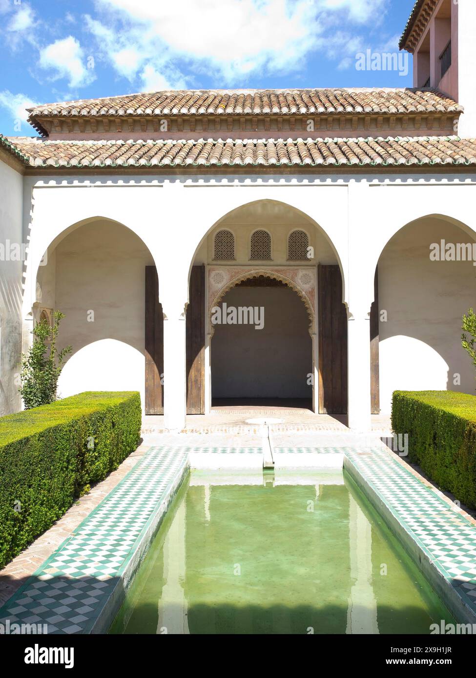 An inner courtyard with archways and a water basin that reflects the ...