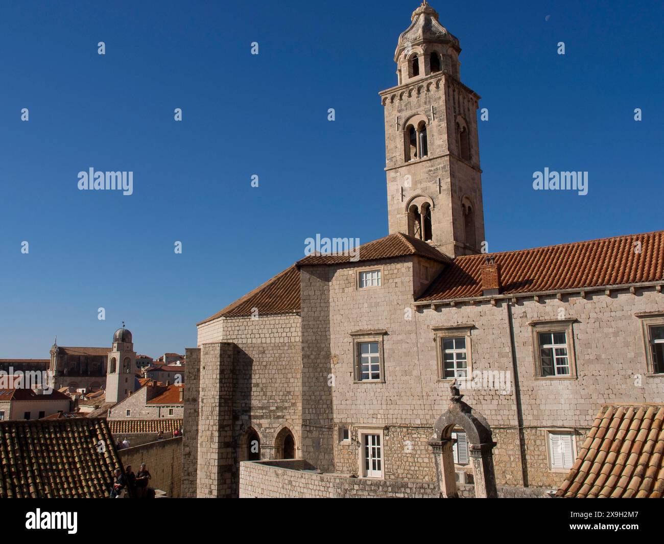Historic stone buildings and a tall tower under a clear blue sky, the ...
