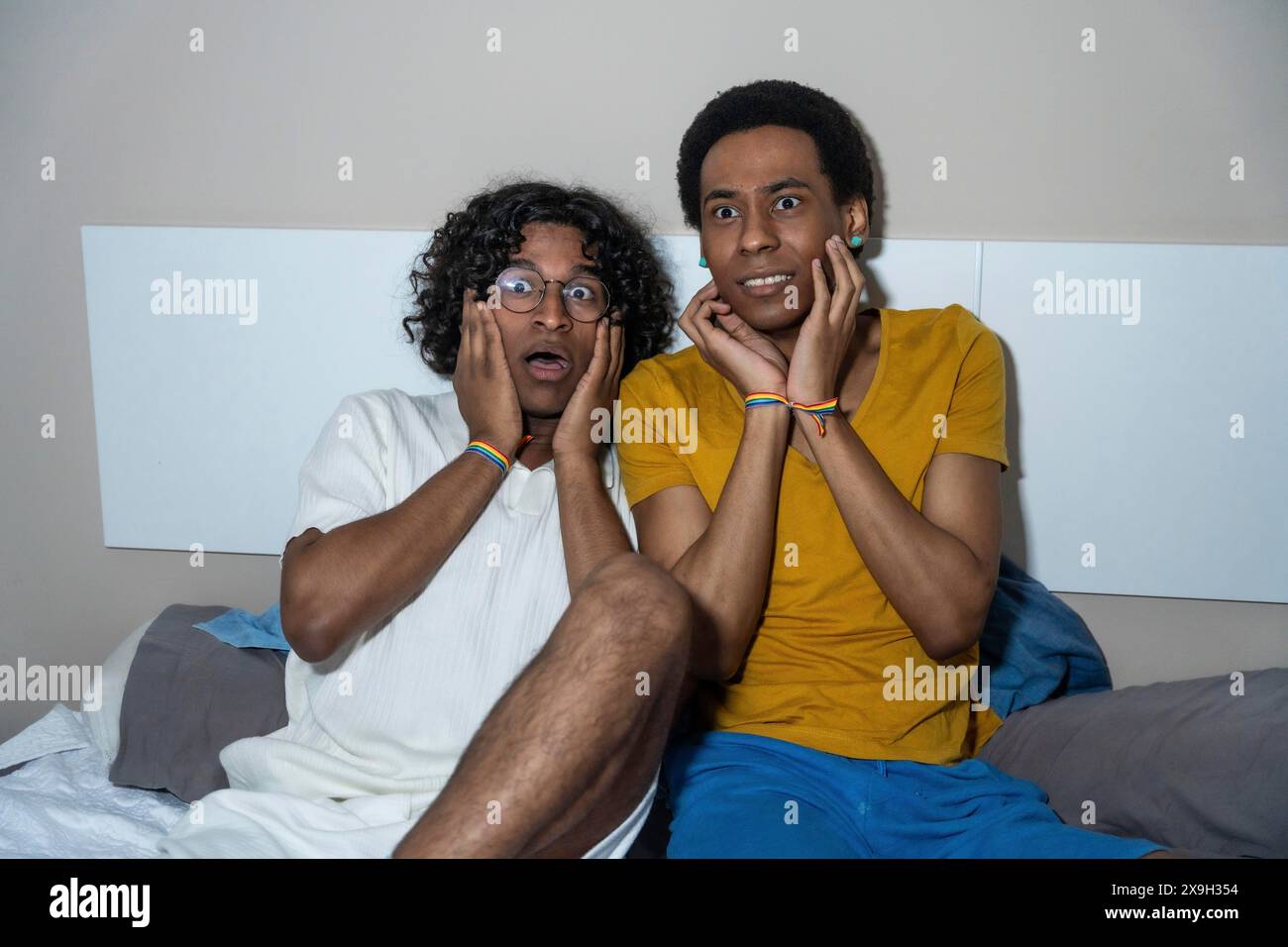 Gay latin male couple watching a horror movie at night at home Stock Photo