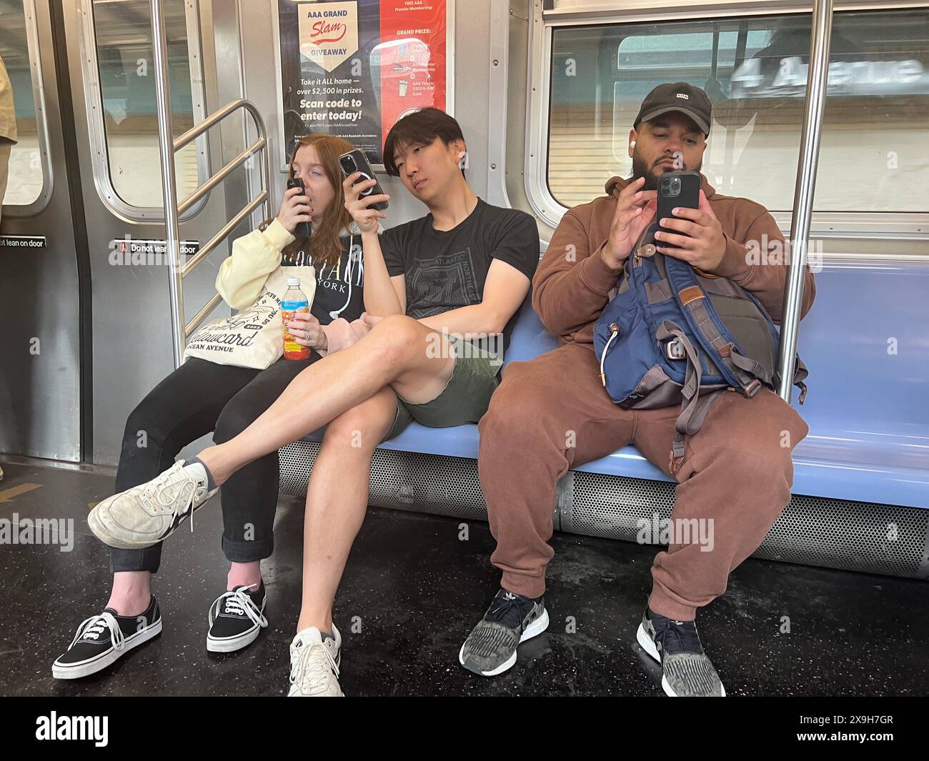 Subway riders engrossed on their phones while riding an F Train in Brooklyn, New York. Stock Photo