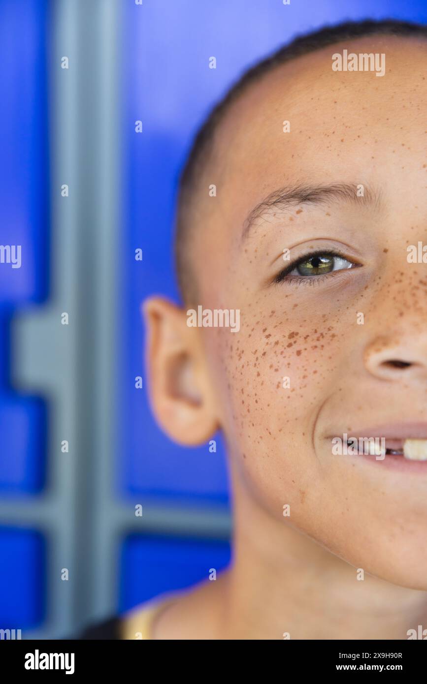 Biracial boy smiles against a blue background in school Stock Photo - Alamy