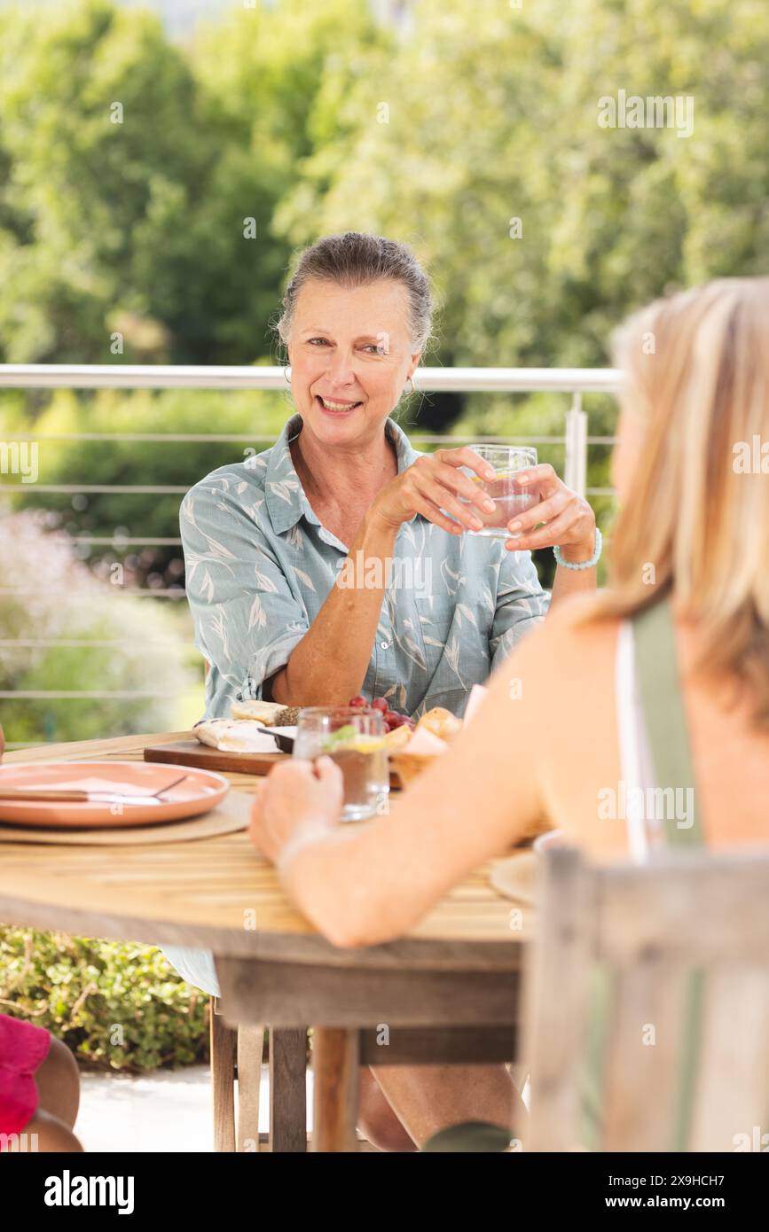 Diverse senior female friends enjoying meal outdoors Stock Photo