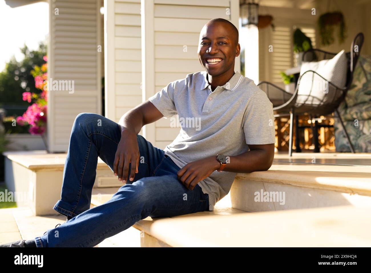 Outdoors, young African American man sitting on steps, smiling warmly ...