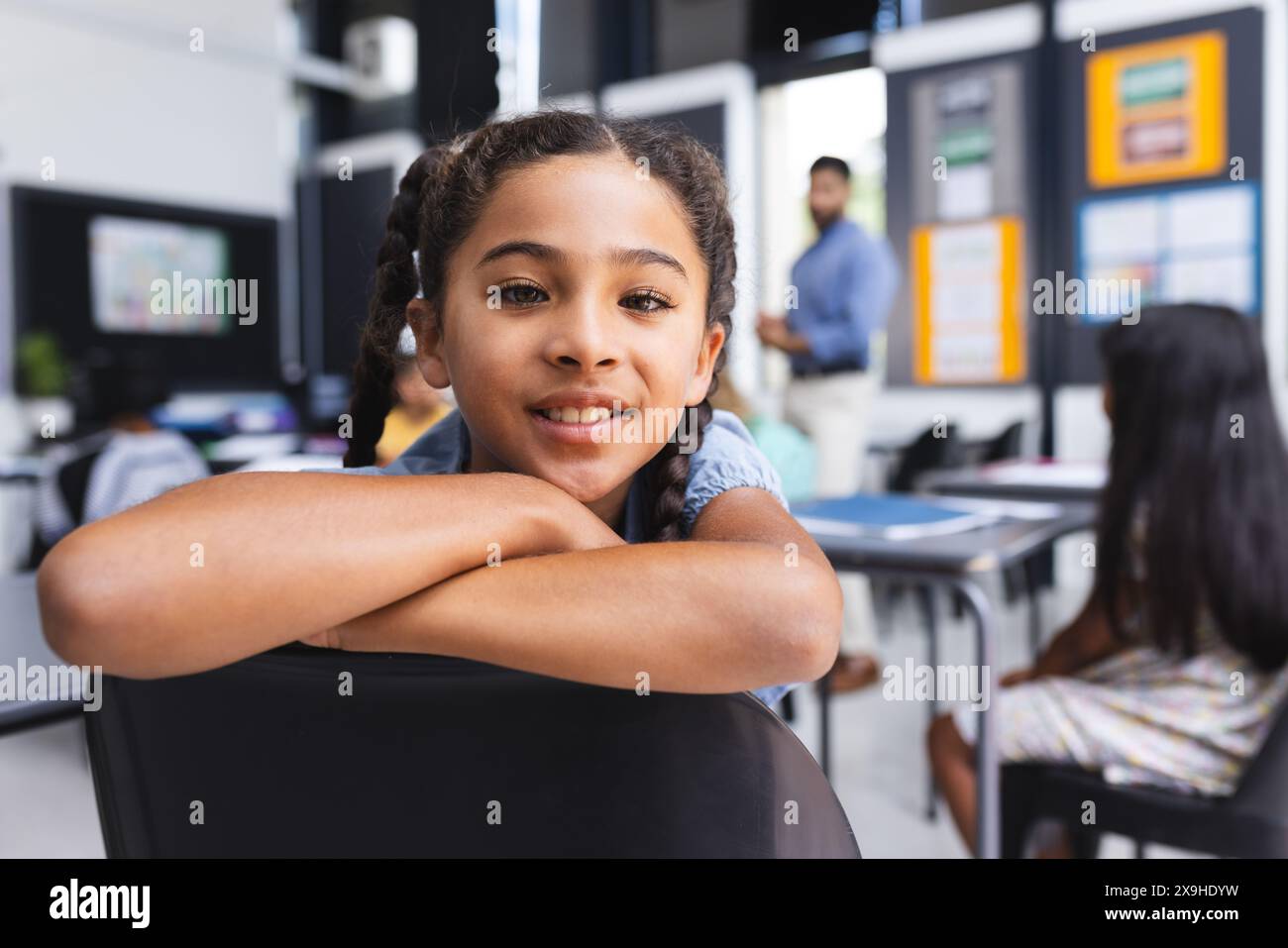 Biracial girl with braided hair smiles in a school classroom Stock Photo