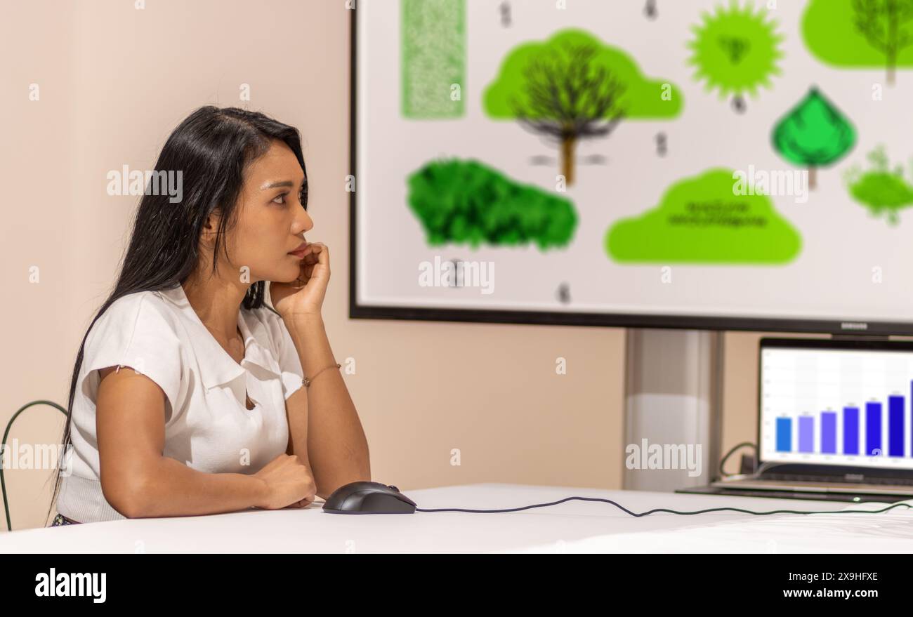A young woman looks at an environmental presentation on the screen Stock Photo