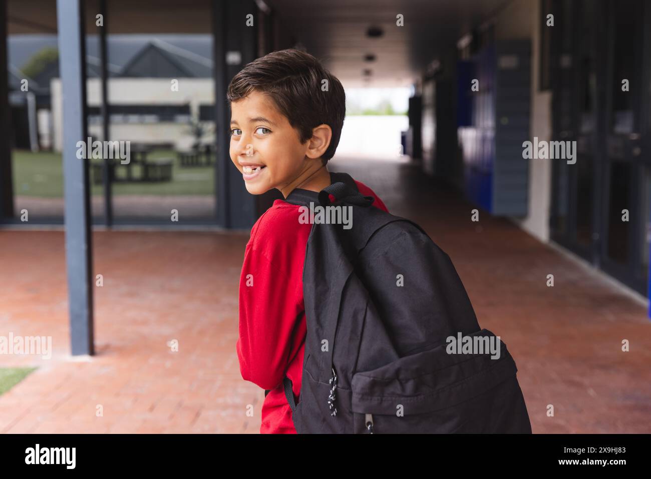 In school, young biracial male student wearing a red shirt is walking ...