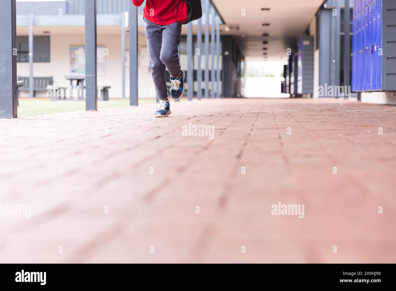 In school, young biracial male student is running along a corridor ...
