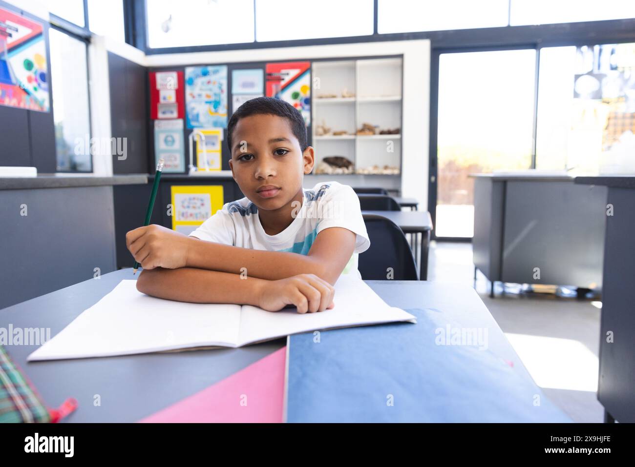 Biracial boy sits at a school desk in a classroom, with copy space, at ...