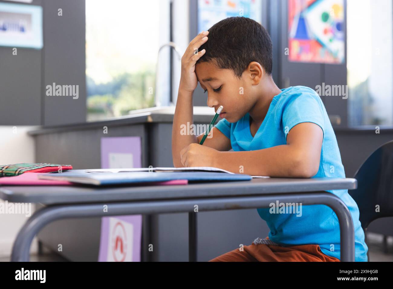 Biracial boy focused on schoolwork in the classroom at school Stock Photo