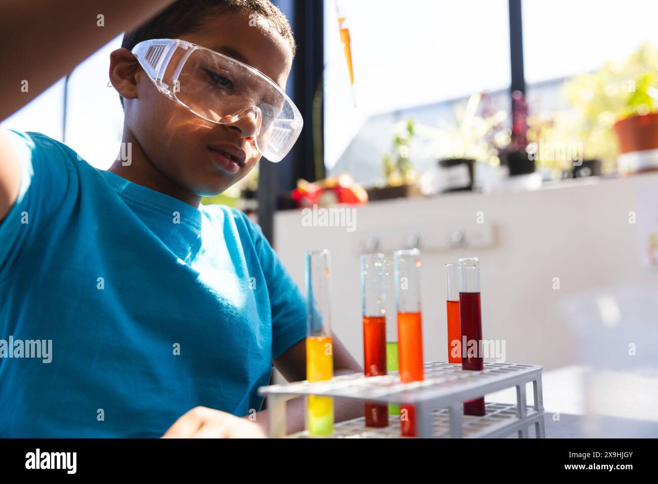 A biracial boy engages in a science experiment at school in the classroom Stock Photo
