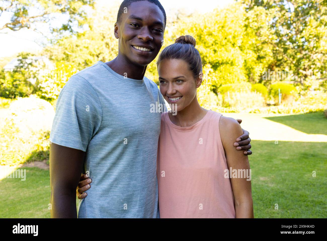 A diverse young couple standing outside, smiling at camera Stock Photo