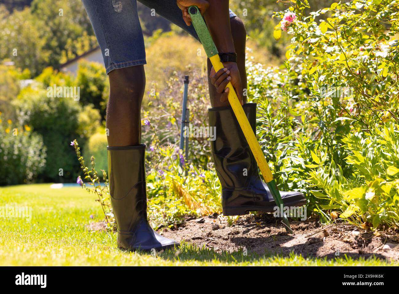 An African American young male, wearing boots, digging outside Stock Photo