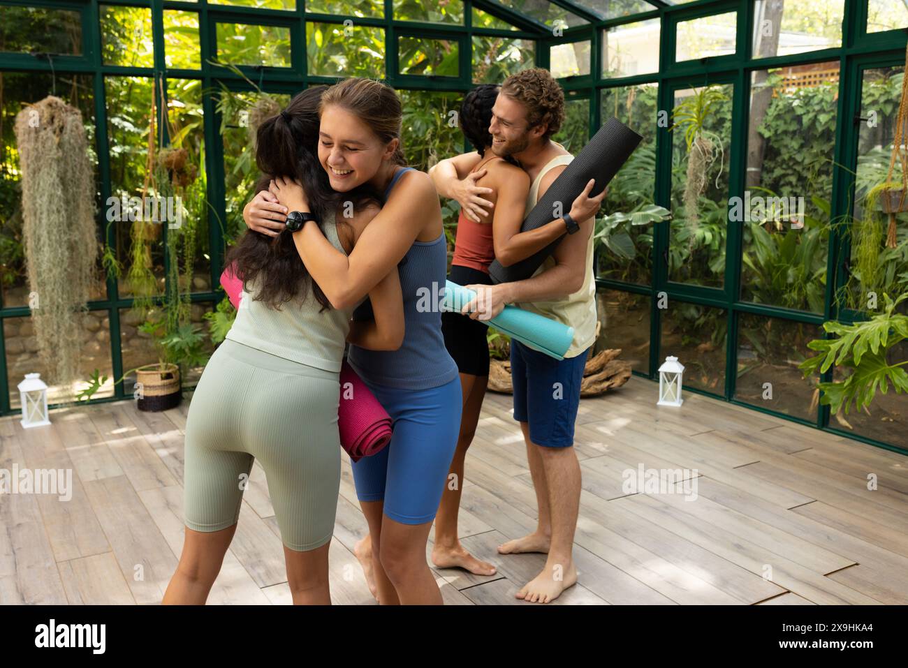 Glass house studio captures diverse yoga students embracing Stock Photo
