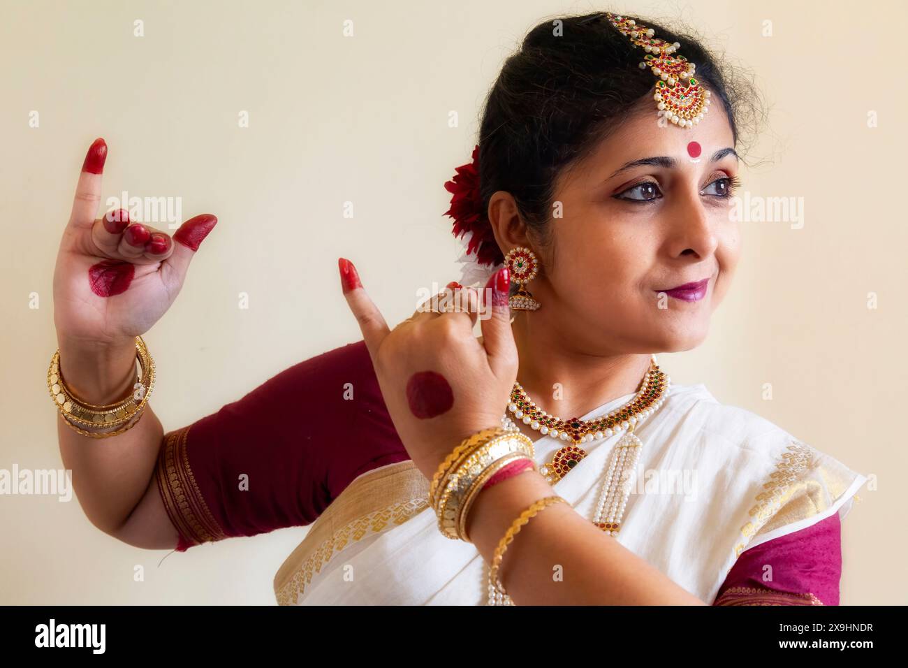 Female Indian classical dancer demonstrating Bharatanatyam classical dance posture on light background Stock Photo