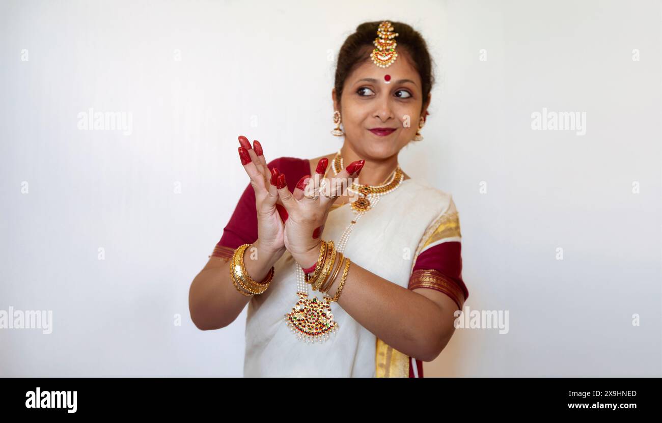 Female Indian classical dancer demonstrating Bharatanatyam classical dance posture on light background Stock Photo