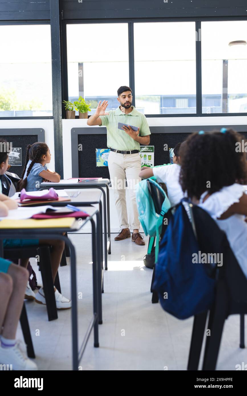 In school, Asian male teacher is explaining to biracial students Stock Photo
