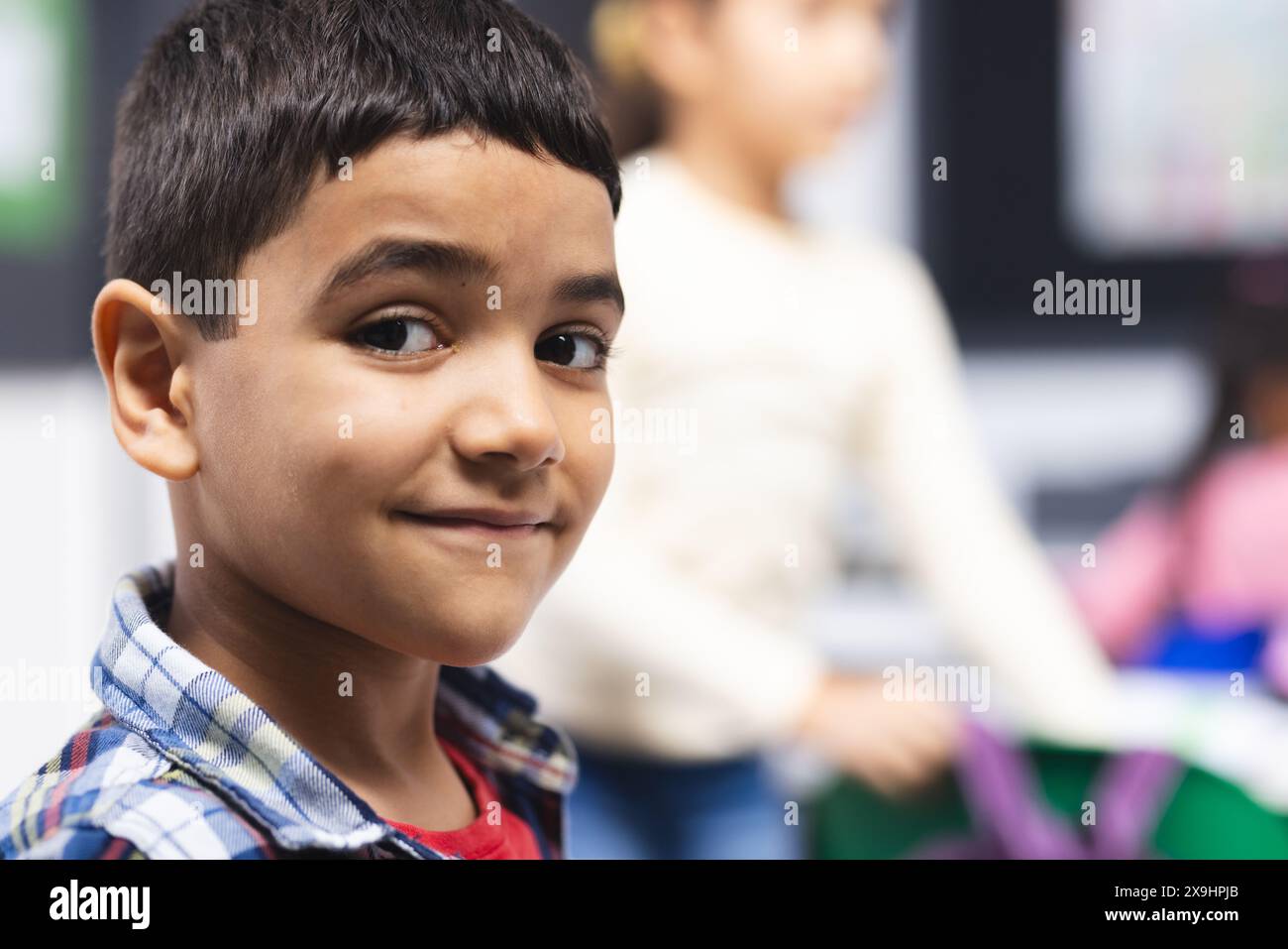 In school, in classroom, young biracial boy is smiling at the camera ...