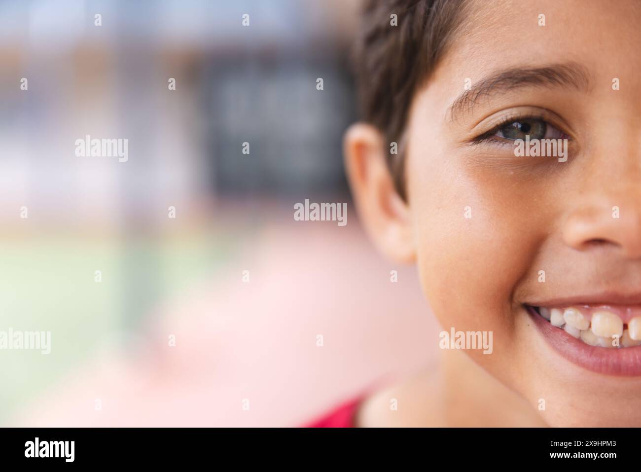In school outdoors, young biracial male student smiling at camera with ...