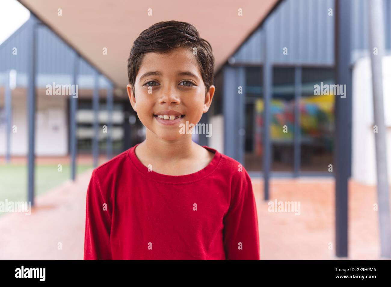In school, biracial young boy with a bright smile standing outside ...