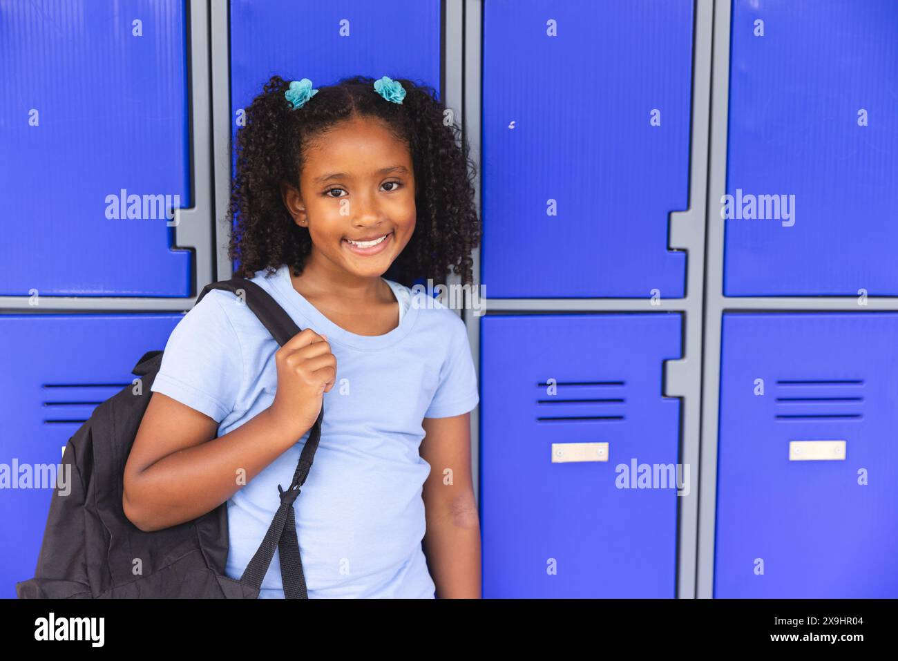 Biracial girl stands by school lockers, with copy space Stock Photo