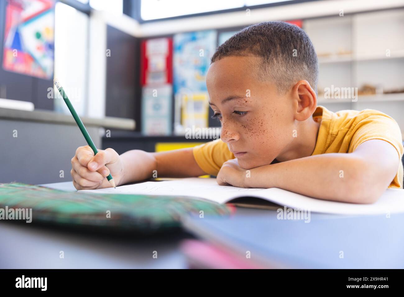 Biracial boy focuses on schoolwork at school Stock Photo - Alamy