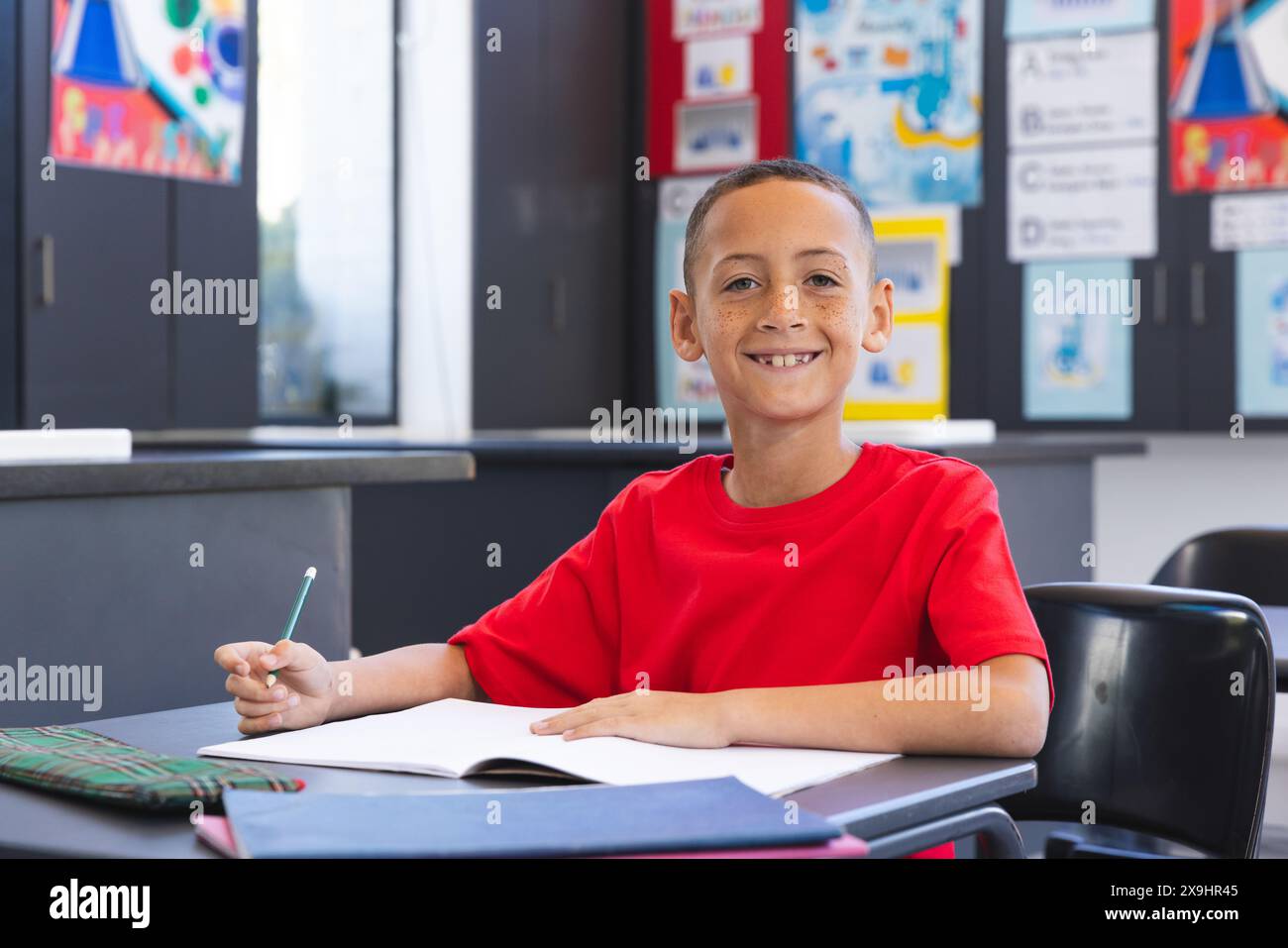 Biracial boy smiles in a classroom setting in school Stock Photo - Alamy