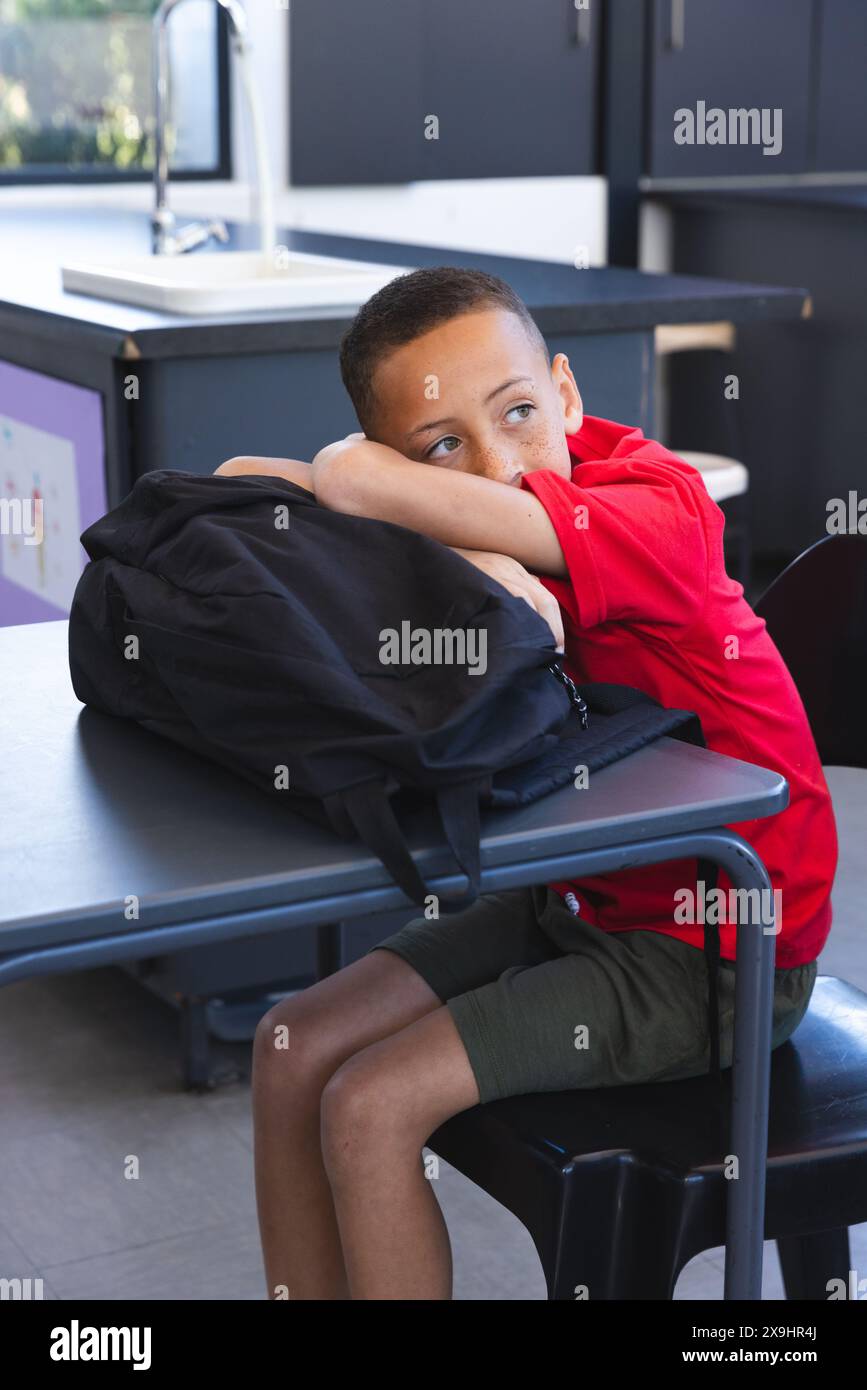 Biracial boy sits at a school desk, looking thoughtful Stock Photo - Alamy