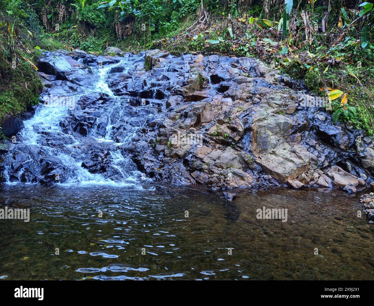 a small cascade in a rocky river flowing like a very small waterfall