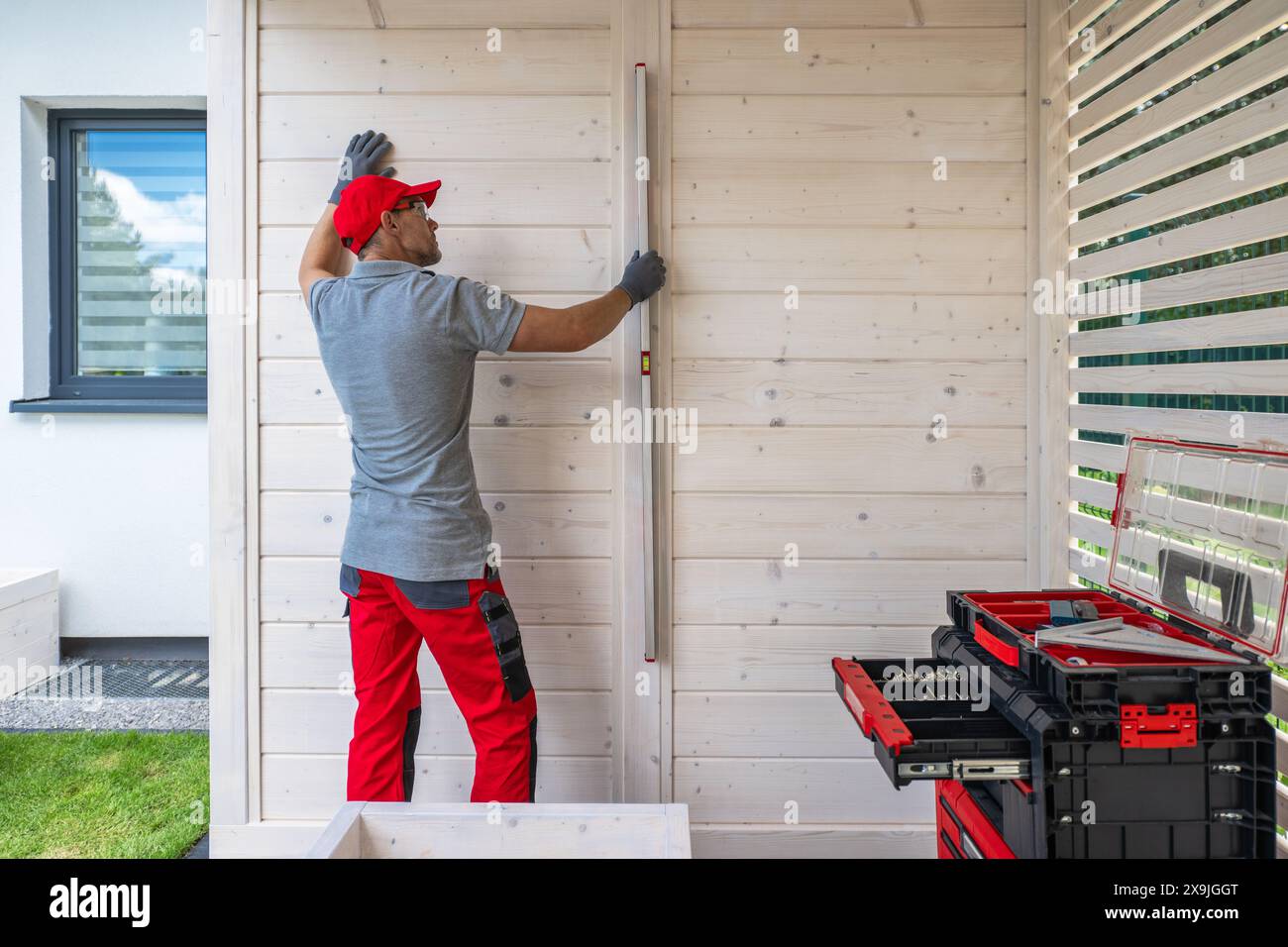 Contractor Using Level on Wooden Wall During Construction Stock Photo