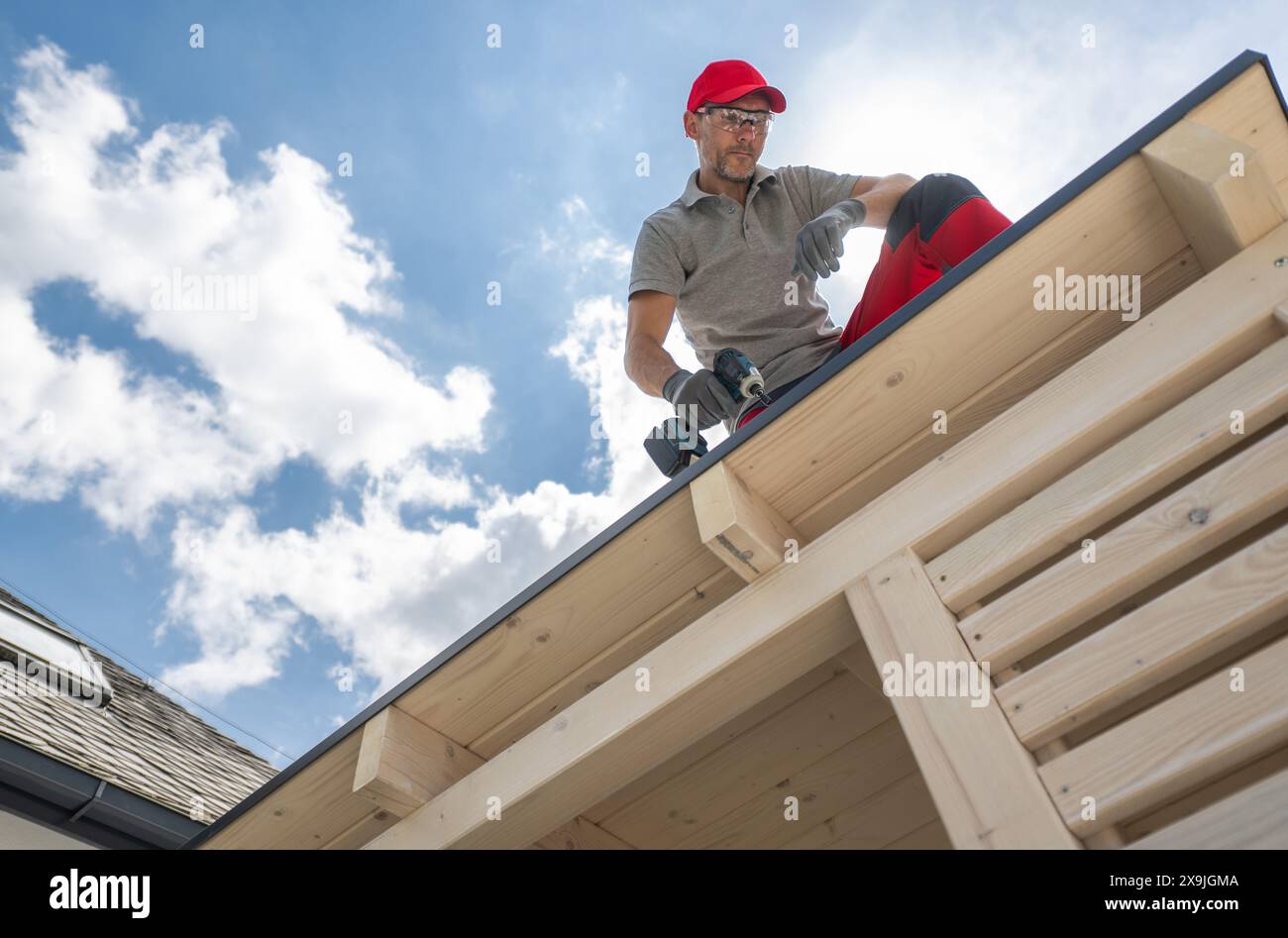 Professional Construction Worker on Roof Using Drill Stock Photo
