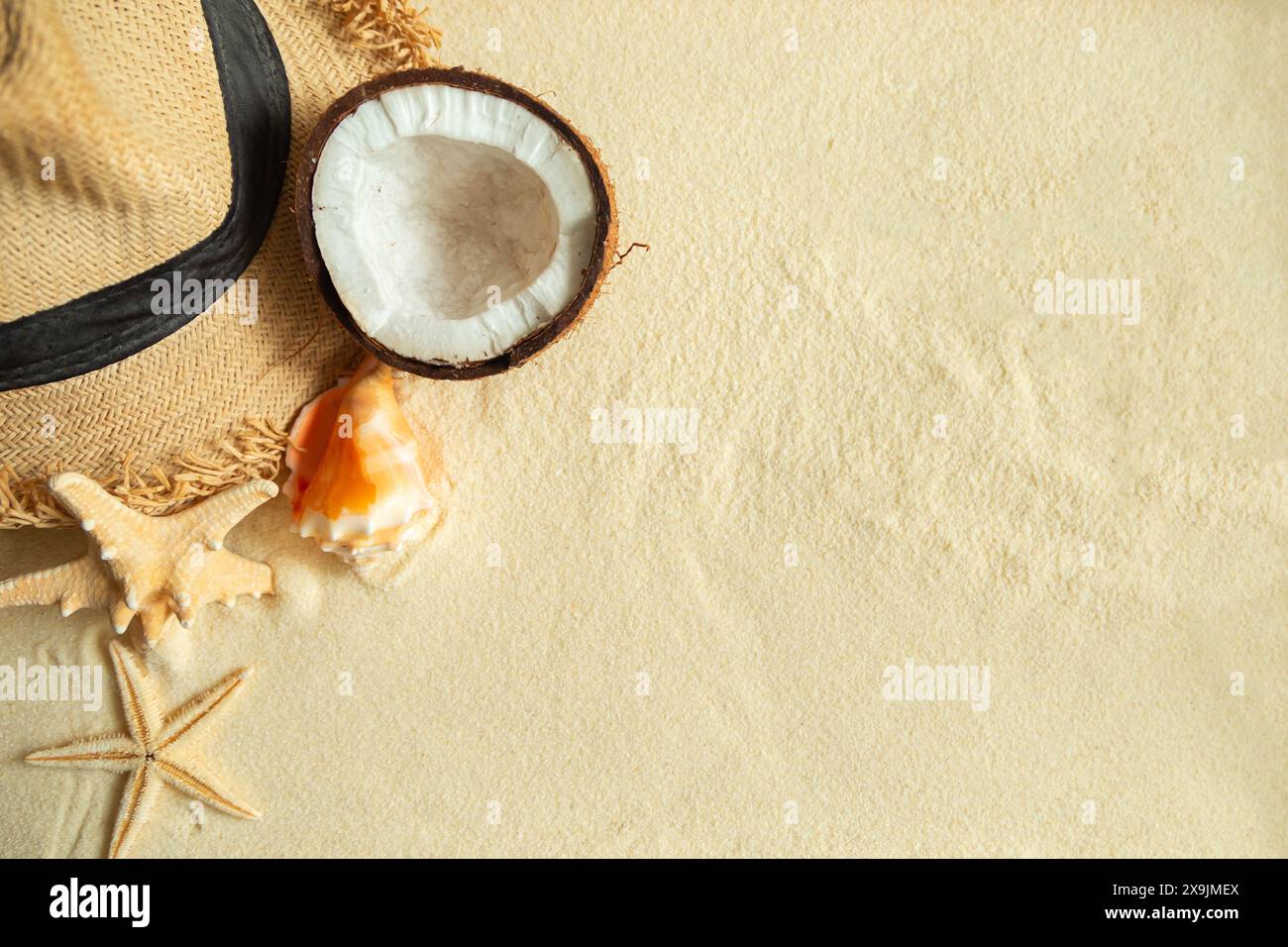 Straw hat, coconut, starfish and shells on white fine sand. Summer ...