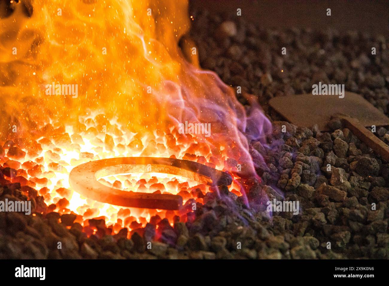 SHEPTON MALLET, SOMERSET, UK. 1st June, 2024,  close up shot of a horseshoe being heated in the fires of a farriers forge. Credit John Rose/Alamy Live News Stock Photo