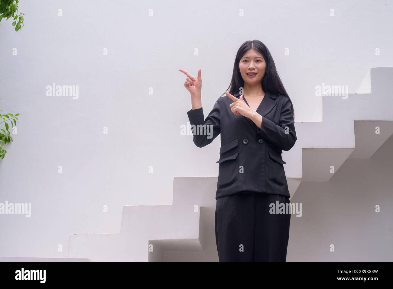 Portrait of a professional woman in business attire exuding confidence on modern architectural steps including greenery Stock Photo