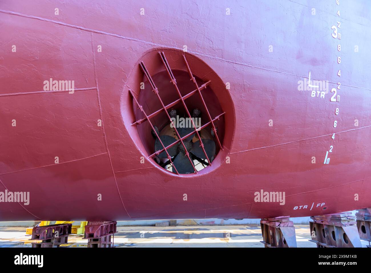 Cargo vessel in dry dock on ship repairing yard. Bow thruster. Stock Photo