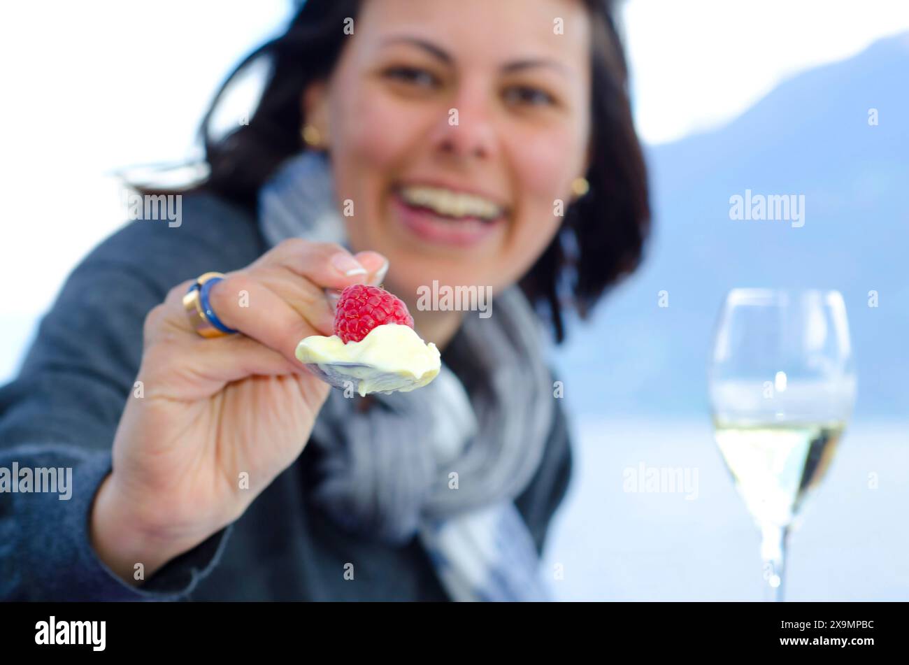 Happy Woman Giving Raspberry Fruit and Ice Cream with a Spoon in Switzerland Stock Photo