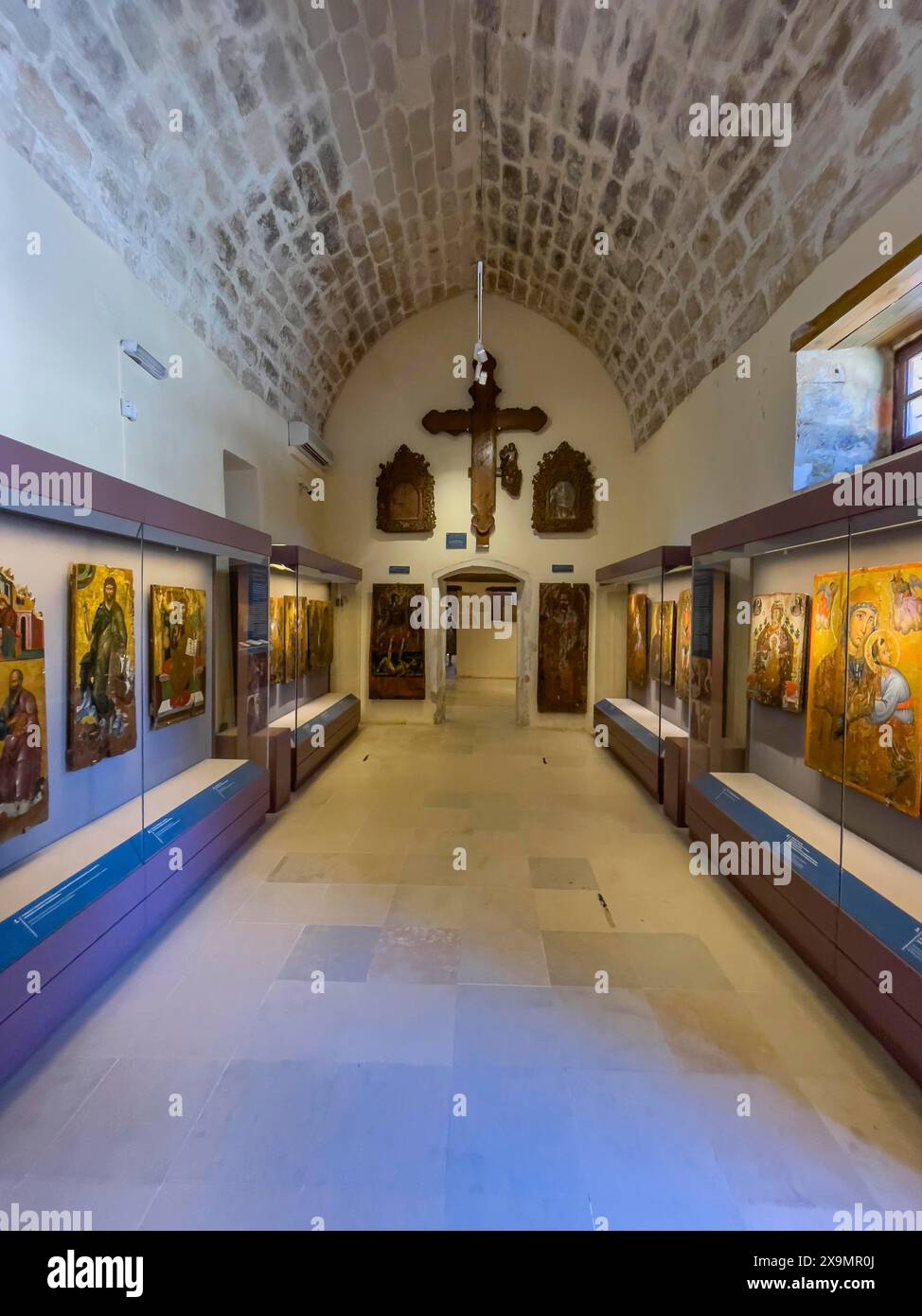 Entrance area with showcases and large wooden cross on wall in vaulted museum Monastery museum in UNESCO World Heritage Site orthodox monastery Moni Stock Photo