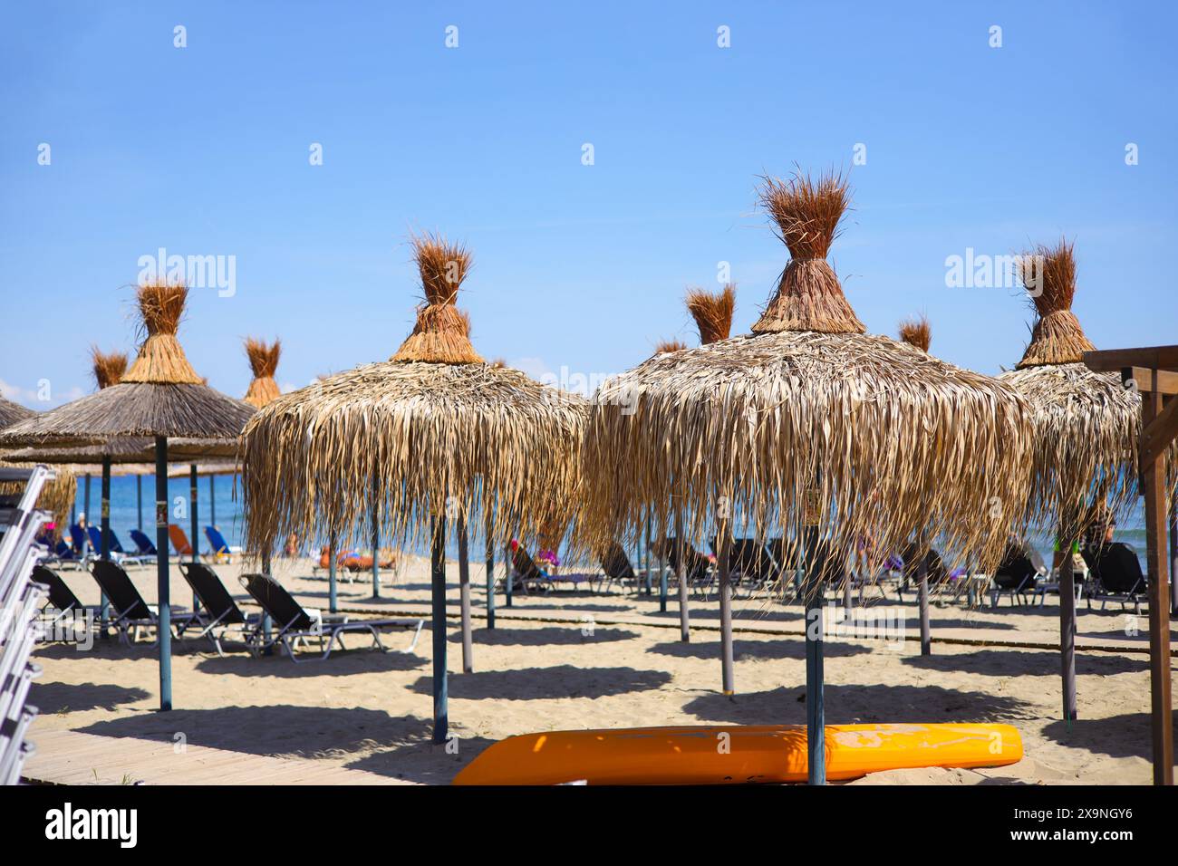 Sandy beach with straw umbrellas and beach loungers on the Olympic ...