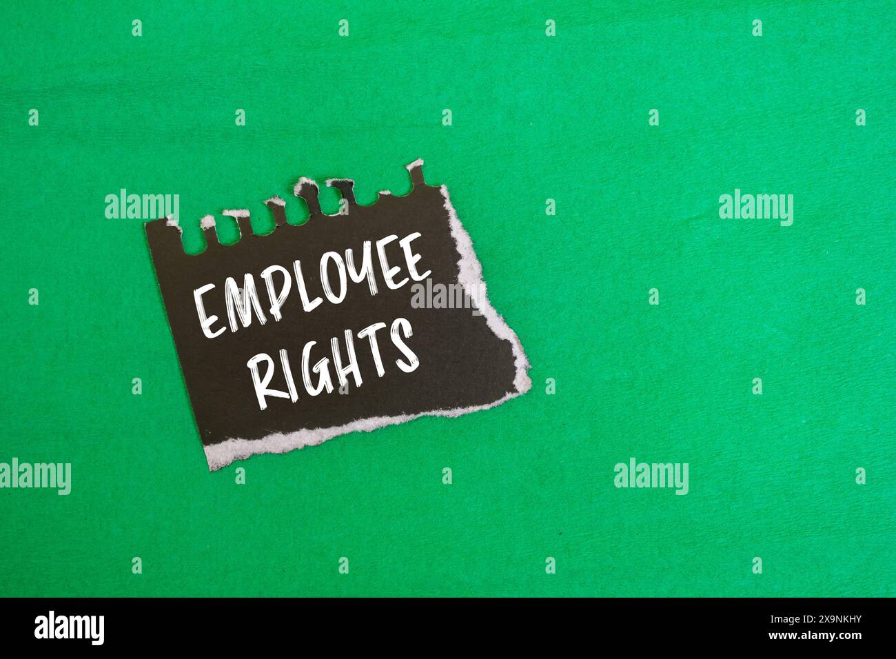 Employee rights message written on ripped black paper piece with green ...