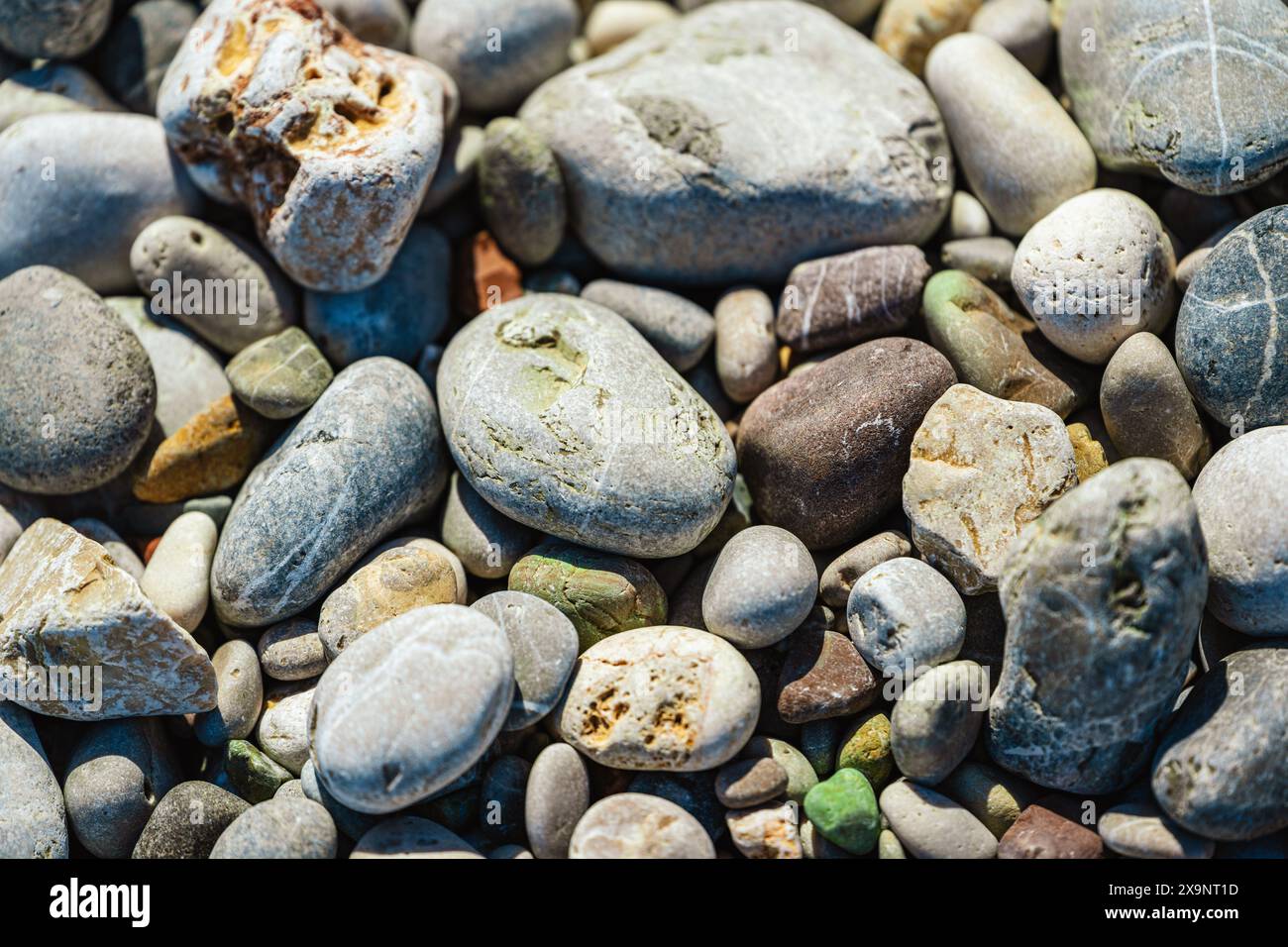 Beach with multicolored small round stones on a sunny day Stock Photo
