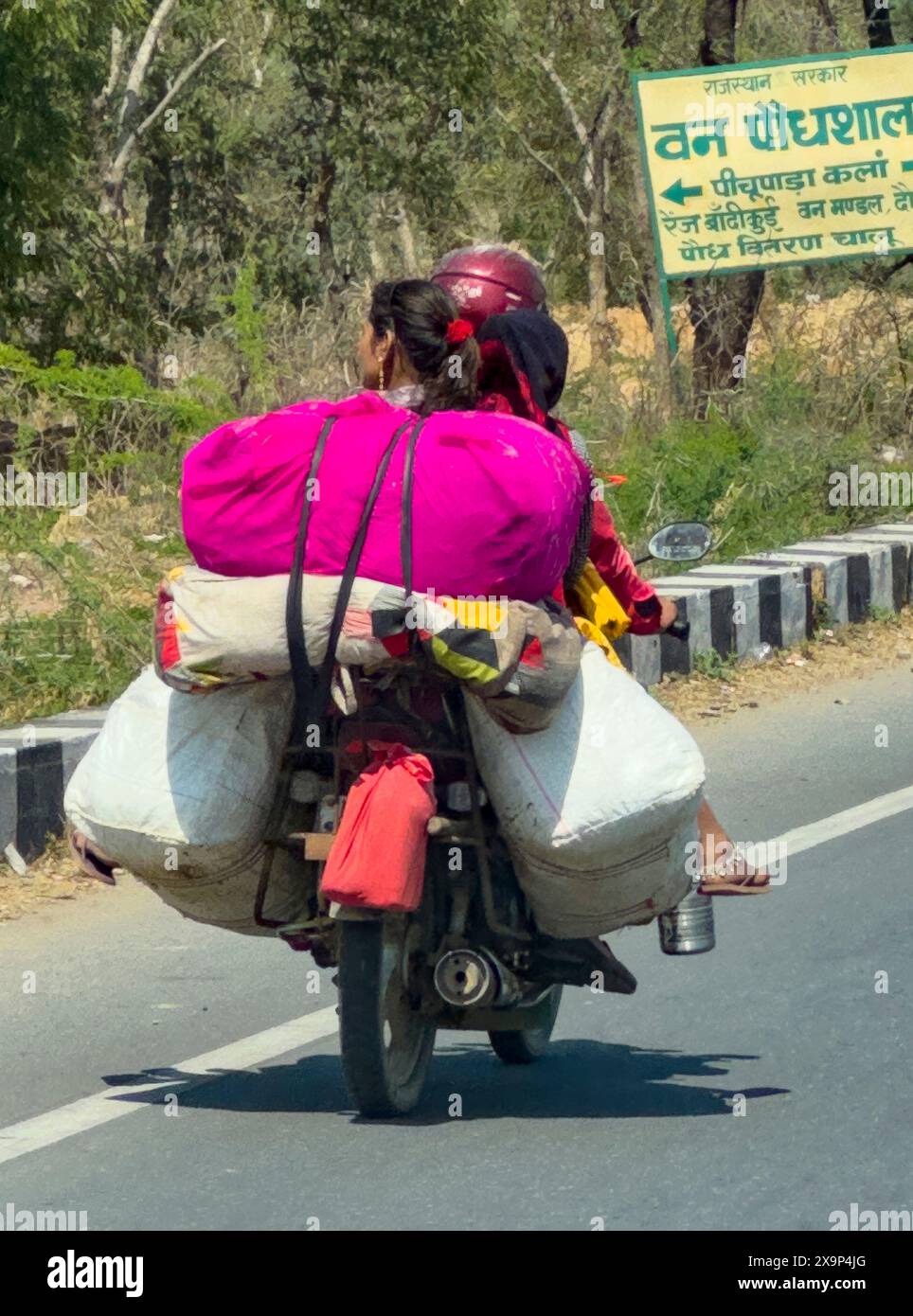 A woman and a child are riding a motorcycle with a sign on the back ...