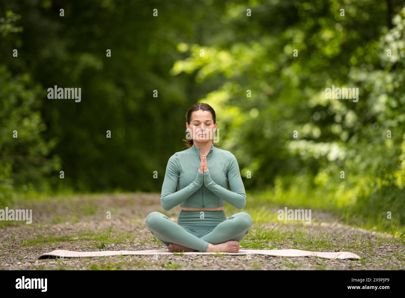 sporty woman performing yoga sitting on mat in lotus position outdoors ...