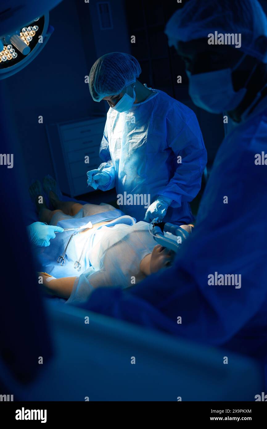 Surgeons in operating room with surgery equipment doing abdominal ...