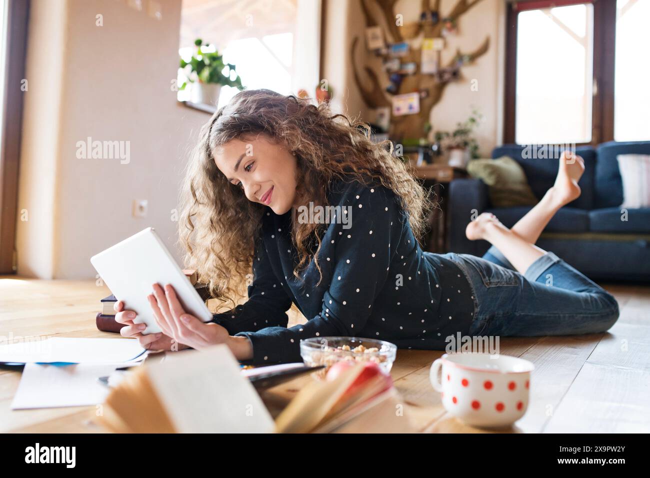 Female student lying on floor, reading books, studying for final exam at university. Beautiful student at home. Stock Photo