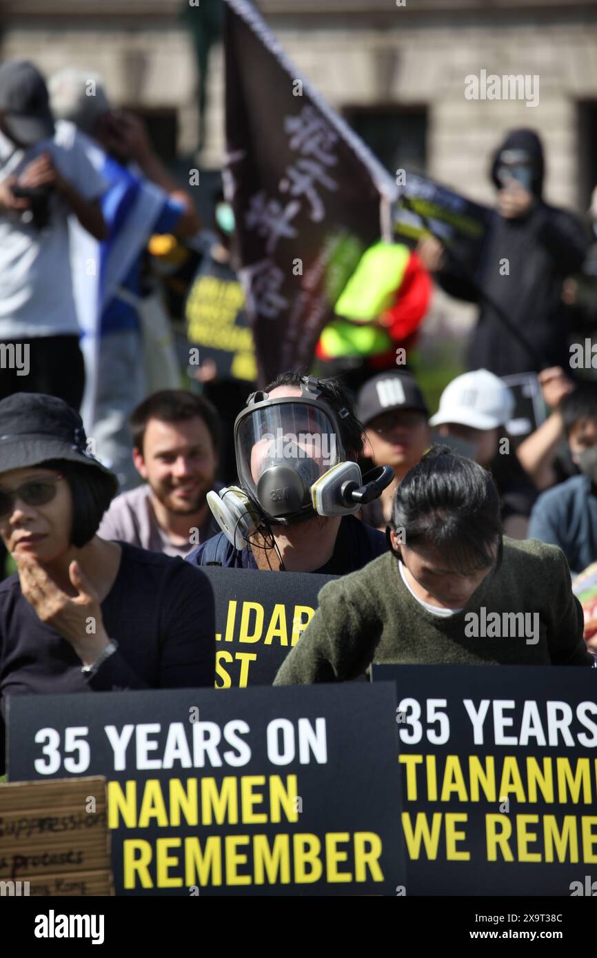 June 2, 2024, London, England, UK: Protesters gather together holding signs supporting their position, one wears a full face mask during the demonstration in Parliament Square. The event commemorated the1989 student-led protests and the Chinese government's bloody crackdown on 4 June, as well as protest against China's current clampdown on freedom of speech - including its increasing repression of Tibetans and Uyghurs, its crushing of dissent in Hong Kong, and the intimidation of Chinese and Hong Kong students in the UK, Europe and North America. Thirty-five years on, the Chinese authorities s Stock Photo