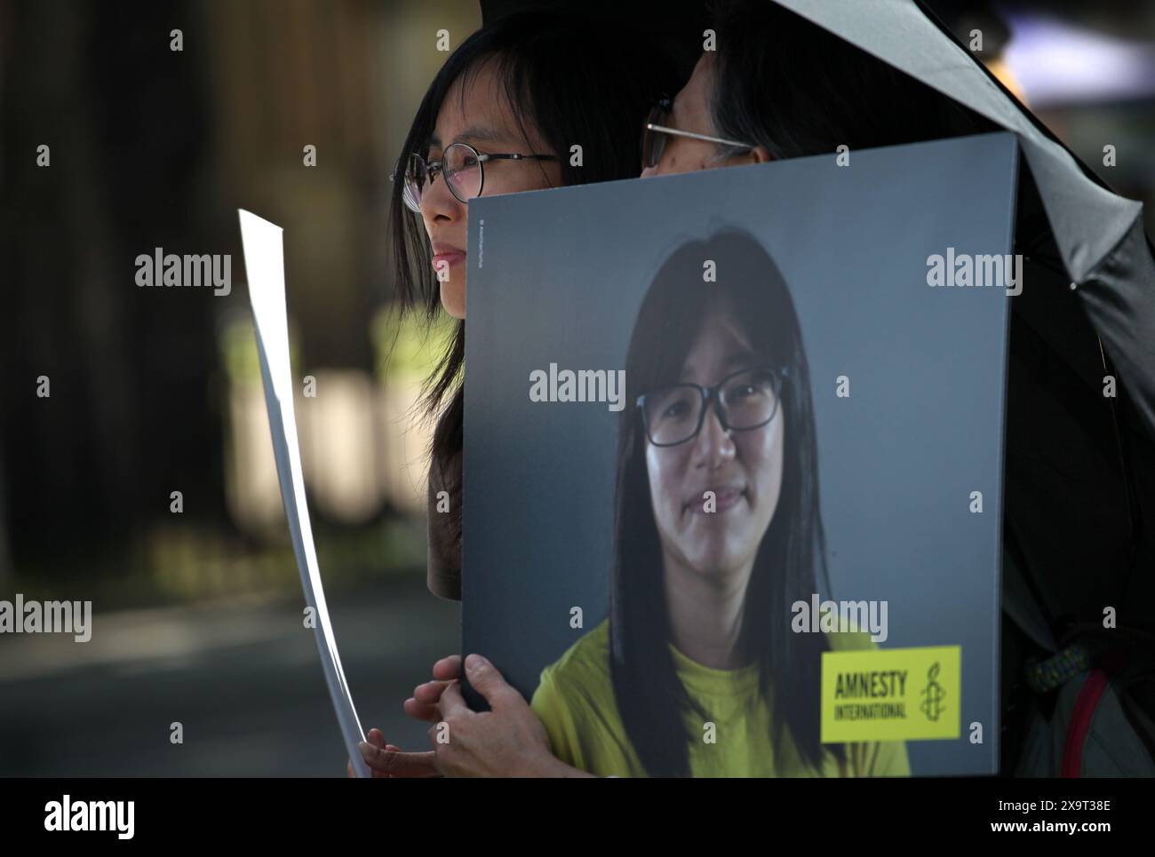 June 2, 2024, London, England, UK: Protesters almost hidden behind signs, one showing a picture of Chow Hang-Tung and under an umbrella during the demonstration in Parliament Square. The event commemorated the1989 student-led protests and the Chinese government's bloody crackdown on 4 June, as well as protest against China's current clampdown on freedom of speech - including its increasing repression of Tibetans and Uyghurs, its crushing of dissent in Hong Kong, and the intimidation of Chinese and Hong Kong students in the UK, Europe and North America. Thirty-five years on, the Chinese authori Stock Photo