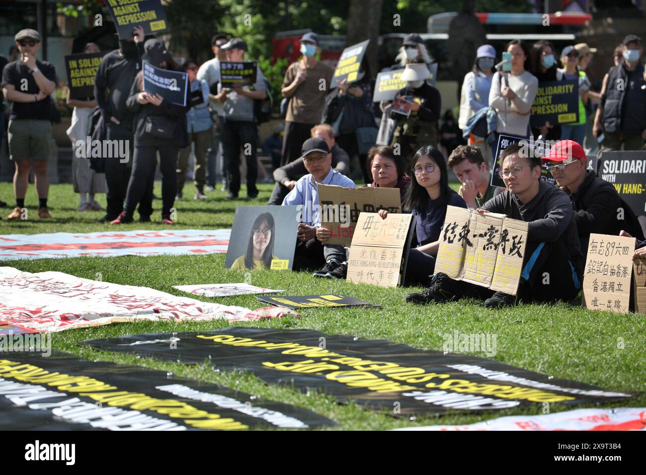 June 2, 2024, London, England, UK: Protesters gather together holding signs supporting their position, while banners are laid on the grass during the demonstration in Parliament Square. The event commemorated the1989 student-led protests and the Chinese government's bloody crackdown on 4 June, as well as protest against China's current clampdown on freedom of speech - including its increasing repression of Tibetans and Uyghurs, its crushing of dissent in Hong Kong, and the intimidation of Chinese and Hong Kong students in the UK, Europe and North America. Thirty-five years on, the Chinese auth Stock Photo