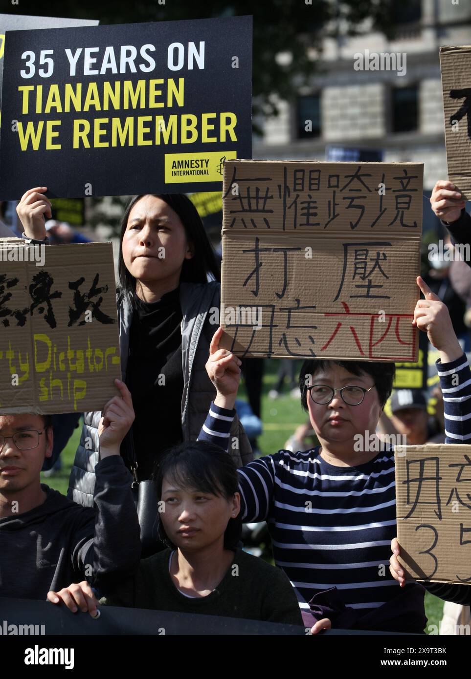 June 2, 2024, London, England, UK: Protesters gather together holding signs supporting their position some in Mandarin, during the demonstration in Parliament Square. The event commemorated the1989 student-led protests and the Chinese government's bloody crackdown on 4 June, as well as protest against China's current clampdown on freedom of speech - including its increasing repression of Tibetans and Uyghurs, its crushing of dissent in Hong Kong, and the intimidation of Chinese and Hong Kong students in the UK, Europe and North America. Thirty-five years on, the Chinese authorities still ban i Stock Photo