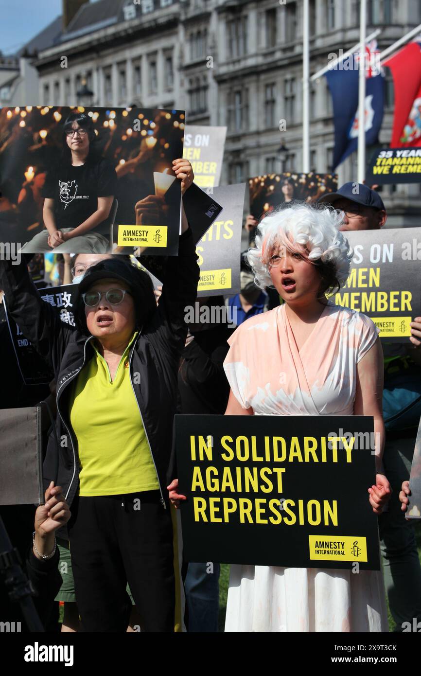 June 2, 2024, London, England, UK: A protester dressed as the Goddess of Democracy holds a sign saying ''˜In Solidarity Against Repression' along with others during the demonstration in Parliament Square. The event commemorated the1989 student-led protests and the Chinese government's bloody crackdown on 4 June, as well as protest against China's current clampdown on freedom of speech - including its increasing repression of Tibetans and Uyghurs, its crushing of dissent in Hong Kong, and the intimidation of Chinese and Hong Kong students in the UK, Europe and North America. Thirty-five years Stock Photo